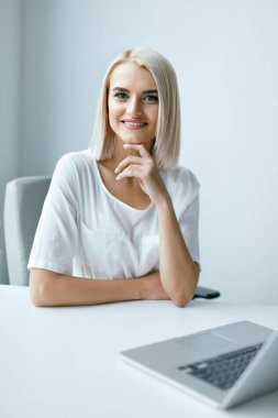 Dizüstü ofiste çalışan genç kadın.