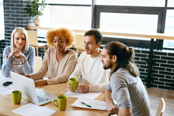 Friends Working Together At Cafe, Using Computer