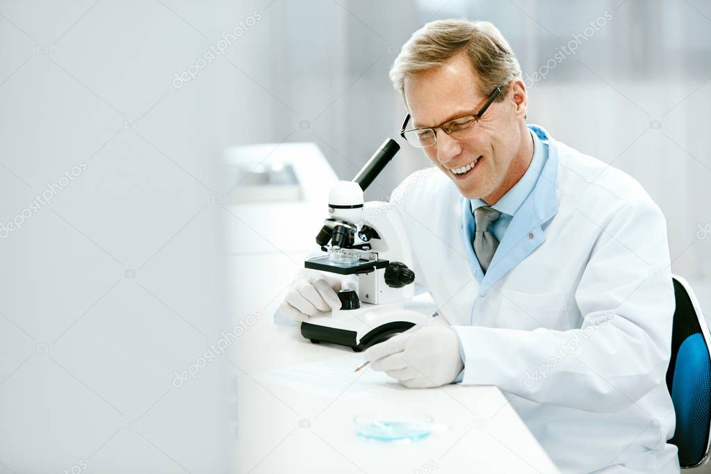 Clinical Test. Scientist With Microscope In Laboratory.
