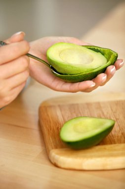 Avokado yeme. Kaşık ile taze avokado soyma kadın eller
