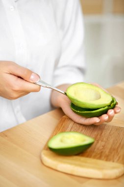 Avokado yeme. Kaşık ile taze avokado soyma kadın eller