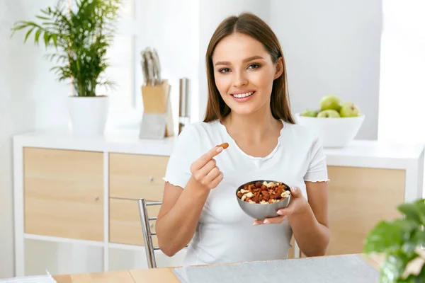 ผู้หญิงที่ยิ้ม กินถั่วในครัว — ภาพถ่ายสต็อก