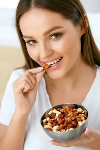 Здоровая пища. Красивая молодая женщина ест орехи — стоковое фото