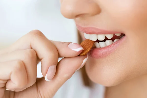 O femeie care mănâncă nuci. Closeup De Femeie Gură Biting Nut . — Fotografie, imagine de stoc