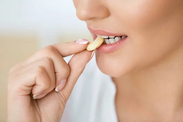 Mujer comiendo nueces. Primer plano de hembra boca mordiendo tuerca . — Foto de Stock