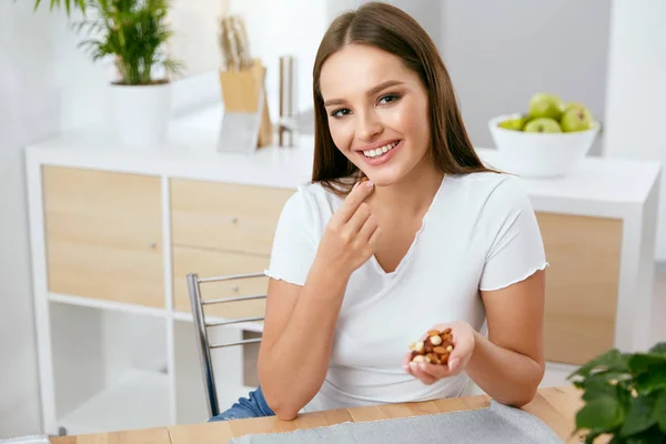 ニコニコ キッチンでナッツを食べる女 — ストック写真
