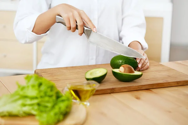 Dieta. Las manos femeninas cortan aguacate en la cocina . —  Fotos de Stock