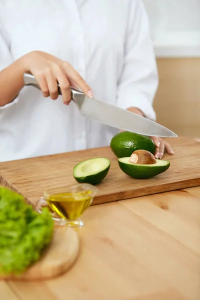 Dieta. Las manos femeninas cortan aguacate en la cocina . —  Fotos de Stock
