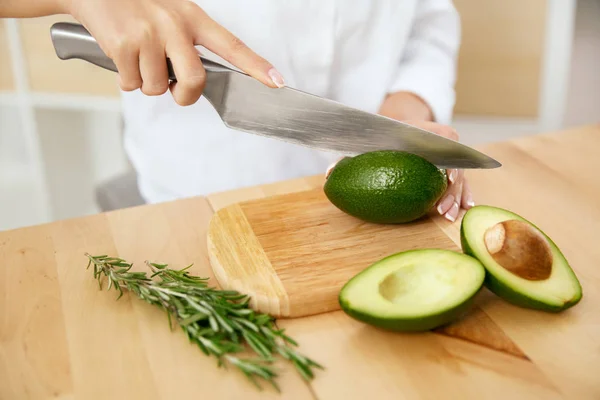 Dieta. Las manos femeninas cortan aguacate en la cocina . —  Fotos de Stock