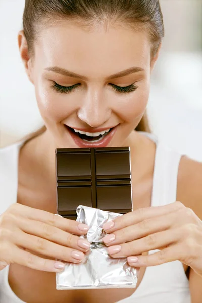 Chocolate. Mulher feliz mordendo Chocolate Bar . — Fotografia de Stock