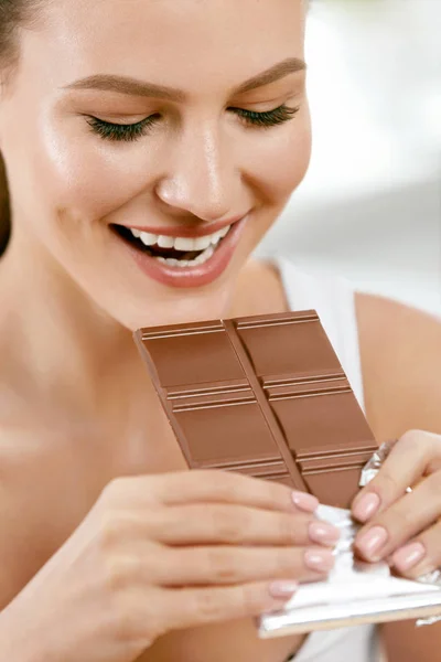 Chocolate. Mujer feliz mordiendo barra de chocolate . —  Fotos de Stock