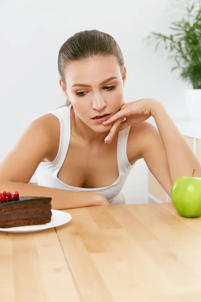 Dieta y Nutrición. Mujer eligiendo entre pastel y manzana . —  Fotos de Stock