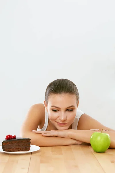 Dieta e Nutrição. Mulher escolhendo entre bolo e maçã . — Fotografia de Stock