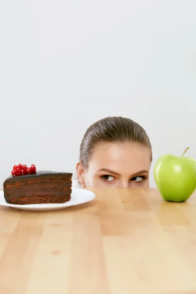 Dieta e Nutrição. Mulher escolhendo entre bolo e maçã . — Fotografia de Stock