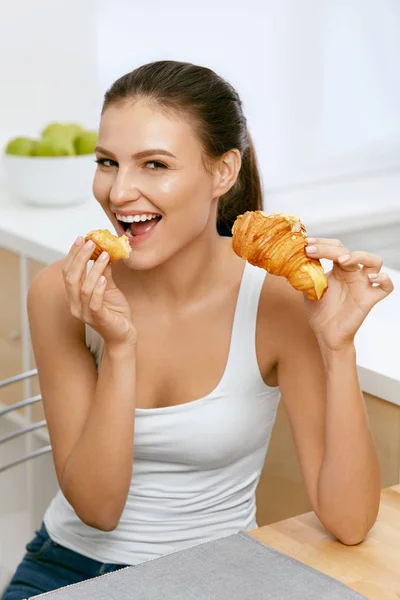 Strava. Šťastná žena jíst rohlík k snídani. — Stock fotografie