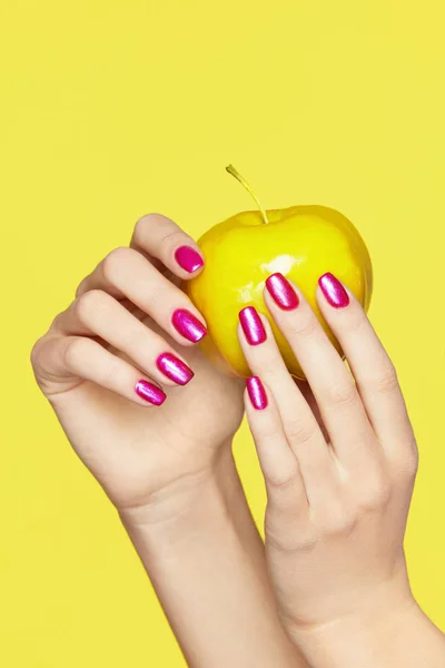 Desenho de unhas. Mãos femininas com unhas coloridas segurando a Apple — Fotografia de Stock