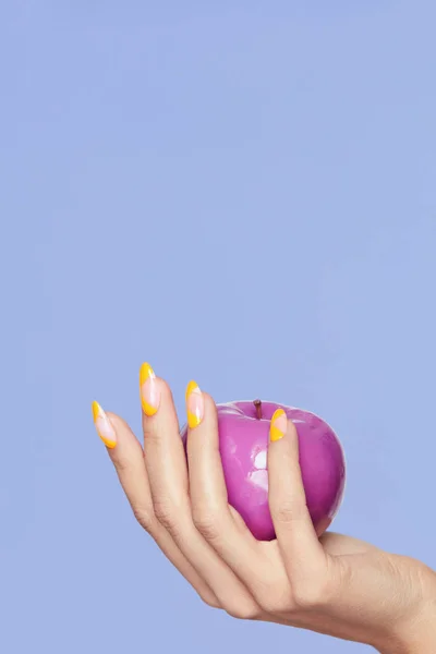 Desenho de unhas. Mãos femininas com unhas coloridas segurando a Apple — Fotografia de Stock