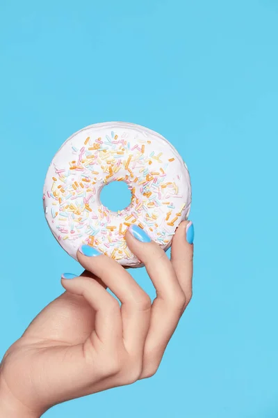 Manicure. Mão com unhas azuis segurando Donut — Fotografia de Stock