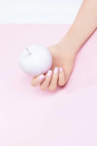 Mano de mujer con uñas de pastel rosa y manzana — Foto de Stock