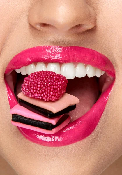ピンクの唇。口の中でお菓子を持つ女性. — ストック写真