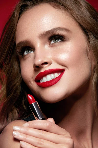 Röda läppar. Vacker kvinna med skönhet smink Holding läppstift. — Stockfoto