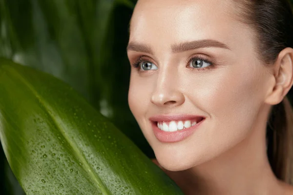 Naturkosmetik. schönes Frauengesicht mit grüner Pflanze — Stockfoto