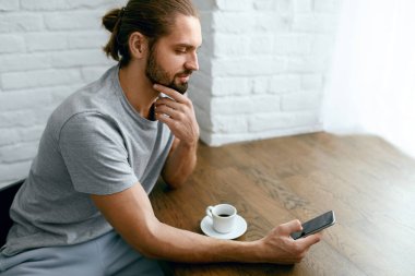Kahve içme ve telefonu kullanarak genç adam