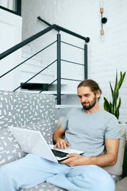 Evde dizüstü bilgisayarı olan genç bir adam..