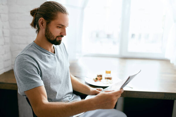 Человек, читающий газету во время завтрака дома
