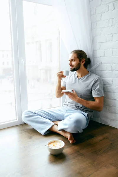 Утренний кофе. Человек наслаждается горячим напитком у окна — стоковое фото