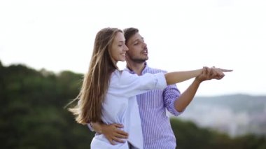 Güzel genç bir çift aşık açık havada. Mutlu genç adam ve kadın manzara, birbirimizi doğada zevk bakarak şık rahat kıyafetler içinde oldukça. Romantik ilişki.