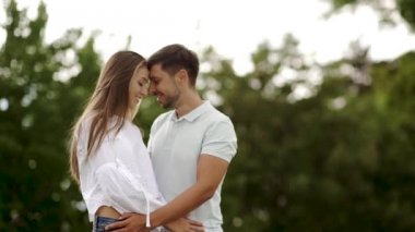 Aşk doğada kucaklayan içinde güzel bir çift. Mutlu kadın ve sarılma ve hafta sonu yaz tadını çıkarırken yakışıklı genç adam portresi. Romantik Tarih açık havada insanlar