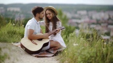 Güzel çift romantik Tarih, birlikte vakit doğada aşık. Sırasında müzik keyfi güzel gülümseyen kadın gitar çalmak yakışıklı genç adam. İnsanlar piknik Park