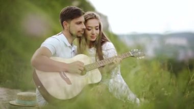 Güzel çift romantik Tarih, birlikte vakit doğada aşık. Sırasında müzik keyfi güzel gülümseyen kadın gitar çalmak yakışıklı genç adam. İnsanlar piknik Park