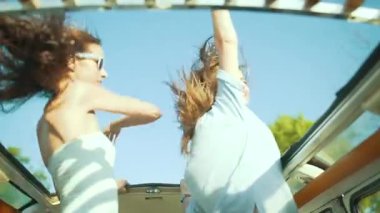 Yaz eğlencesi. Rüzgar, hafta sonu yaz aylarında seyahat araba kızlarda. Güzel mutlu genç kadınlar kıllı açık araba çatı dans ve Having Fun yaz aylarında mavi gökyüzü Rüzgar.