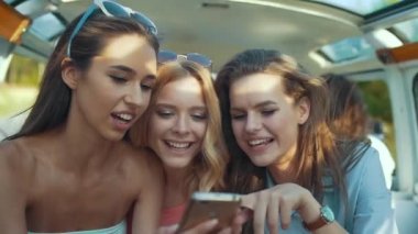 Mutlu arkadaş yaz aylarında eğleniyor seyahat telefon kullanarak arabaya. Yaz aylarında seyahat tatil zevk güneşli yaz gününde üstünde hareket eden telefon fotoğraf çekmek güzel gülümseyen kız.