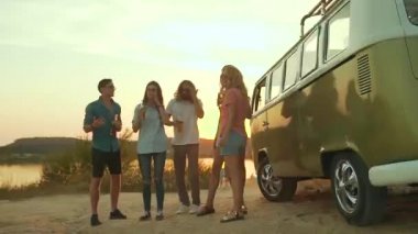 Dans ve doğada içme genç arkadaşlar. Güzel mutlu insanlar içecekler yaz hafta sonu eğleniyor. Retro otobüs yakınındaki dış taraf zevk arkadaş.
