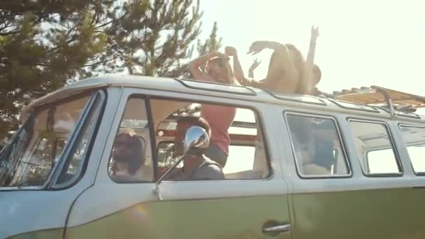 在车上的朋友在露天的屋顶玩得开心 愉快的微笑的年轻人跳舞在复古公共汽车与开放汽车屋顶在夏天天 — 图库视频影像