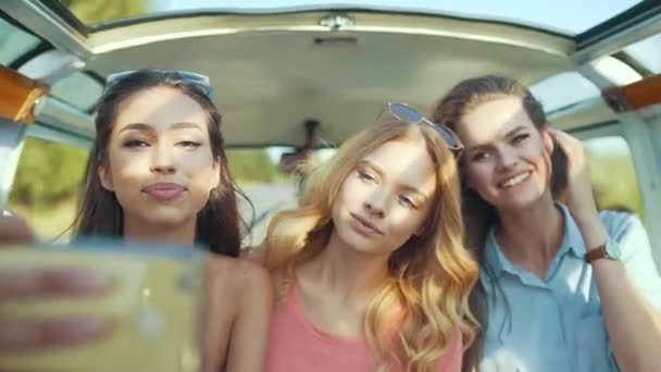 楽しんで幸せな友人は 携帯電話を使用して 車で旅行します 日当たりの良い夏の日 夏の休暇旅行を楽しむ携帯電話で写真を撮って美しい笑顔の女の子 — ストック動画