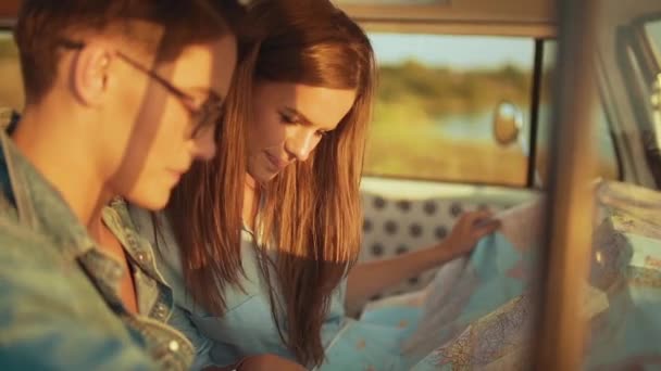 夏に車でマップを使ってカップル旅行 幸せな笑顔の若い人は夏休みの旅行を使用して地図表示 ハンサムな男と美女の旅行を持っていること — ストック動画