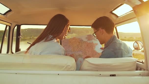 Přátelé pomocí mapy cestování v autě v létě. Pohledný muž v brýlích a krásnou usmívající se žena držící mapu v rukou přitom cesta venku. Mladí lidé cestování o víkendu