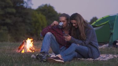 Turist çift cep telefonu, doğada kamp yakınındaki romantik kaçamaklar sahip bakarak aşık.