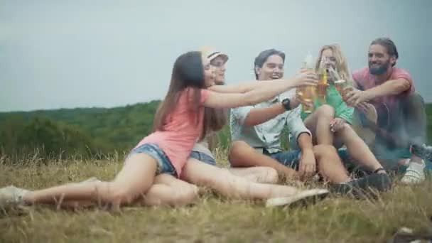 快乐的年轻朋友喝啤酒 有乐趣 坐在附近的篝火野餐户外 — 图库视频影像