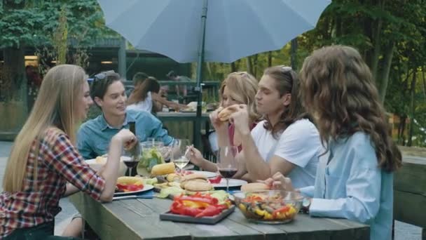 Felices Jóvenes Amigos Comiendo Hamburguesas Sentados Mesa Cena Barbacoa Aire — Vídeo de stock