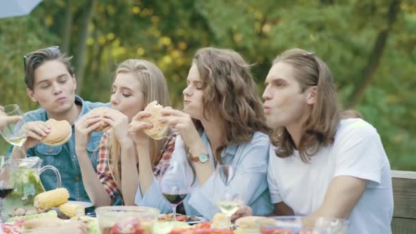 Felices Jóvenes Amigos Comiendo Hamburguesas Sentados Mesa Cena Barbacoa Aire — Vídeo de stock