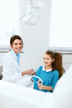 Diş sağlığı. Diş hekimi ve diş hekimliği ofiste mutlu kız