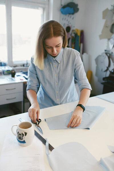 Портной резки ткани с ножницами в Atelier
