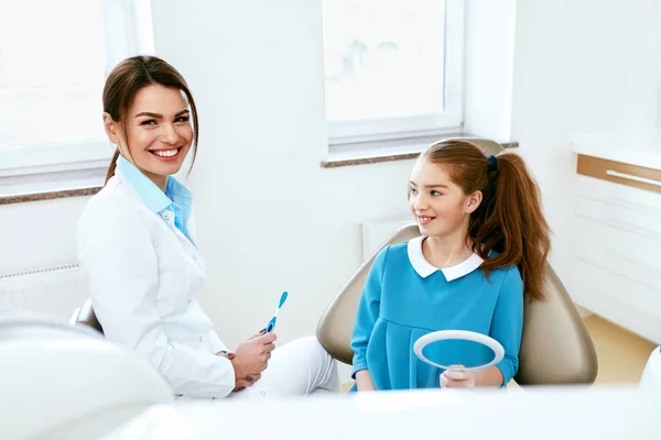 Tandhälsa. Tandläkare och glad tjej i tandvård kontor — Stockfoto