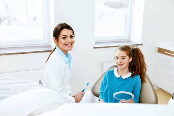Tandhälsa. Tandläkare och glad tjej i tandvård kontor — Stockfoto