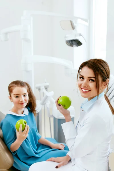 Clinica dentistica. Dentista femminile e piccolo paziente mangiare mela — Foto Stock